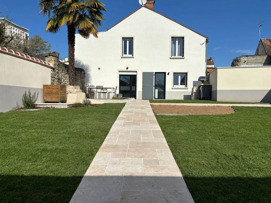 Jardin méditerranéen avec massif fleuri en premier plan : échinacées roses, achillées jaunes, gypsophile blanc, lavande coton argentée, sur paillage minéral